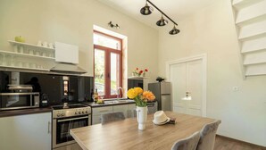 A modern kitchen with stainless steel appliances, a wooden dining table, and a window with a view. - Casa Chris (Chania)