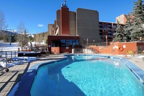 Una piscina con vistas a un edificio de fachada roja y un telesilla de fondo.