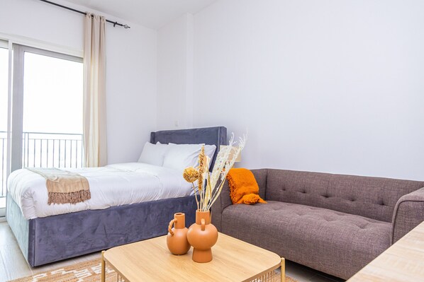 Une chambre à coucher avec un lit, un canapé et deux vases posés sur une table.