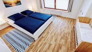A bedroom with a bed, a radiator, a window, and a painting on the wall.