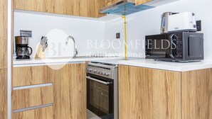 Een moderne keuken met houten kastjes, een ingebouwde oven, een magnetron en een koffiezetapparaat.