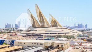 Um estádio grande com uma estrutura de cobertura única, cercado por canteiros de obras e edifícios.