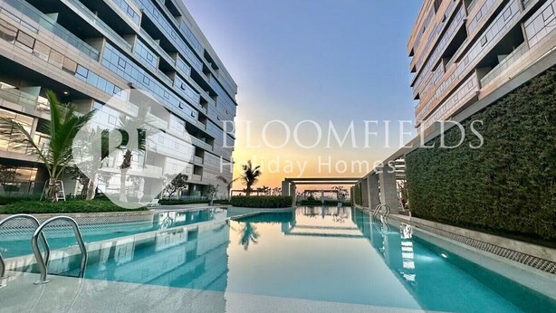 A modern residential building with a swimming pool, surrounded by greenery and palm trees.