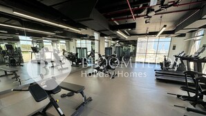 A gym with various exercise equipment, large windows, and a modern industrial design.