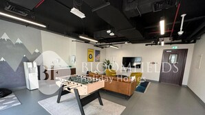 A modern indoor space with a foosball table, a sofa, and a television.