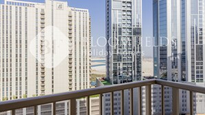 A high-rise residential building with multiple balconies and a clear view of the beach.