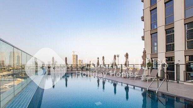 A rooftop swimming pool with lounge chairs and umbrellas, surrounded by high-rise buildings.