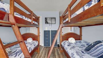 A room with two bunk beds, a dresser, and a framed picture on the wall.