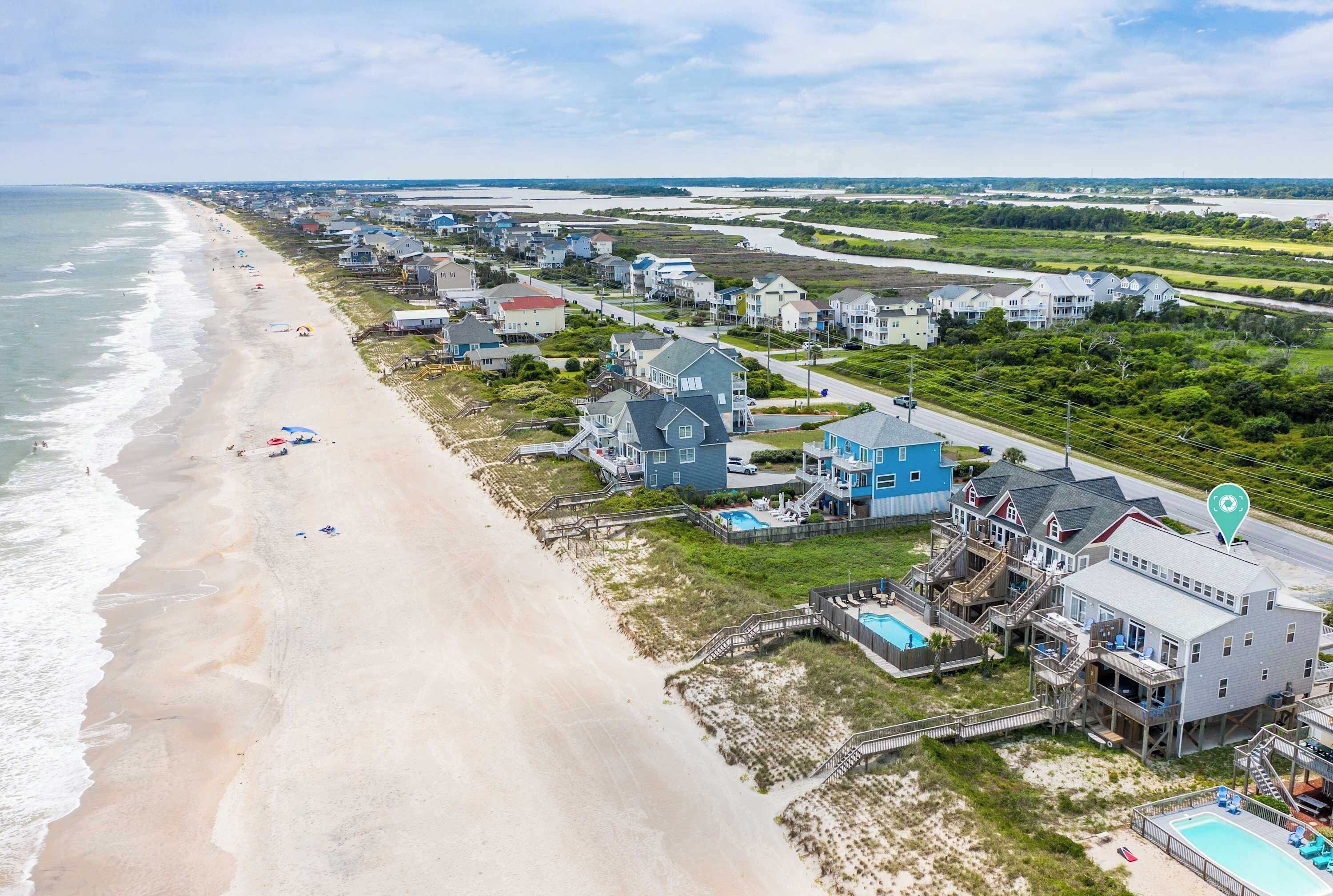 A coastal residential area with beachfront properties, including houses with balconies and a swimming pool.