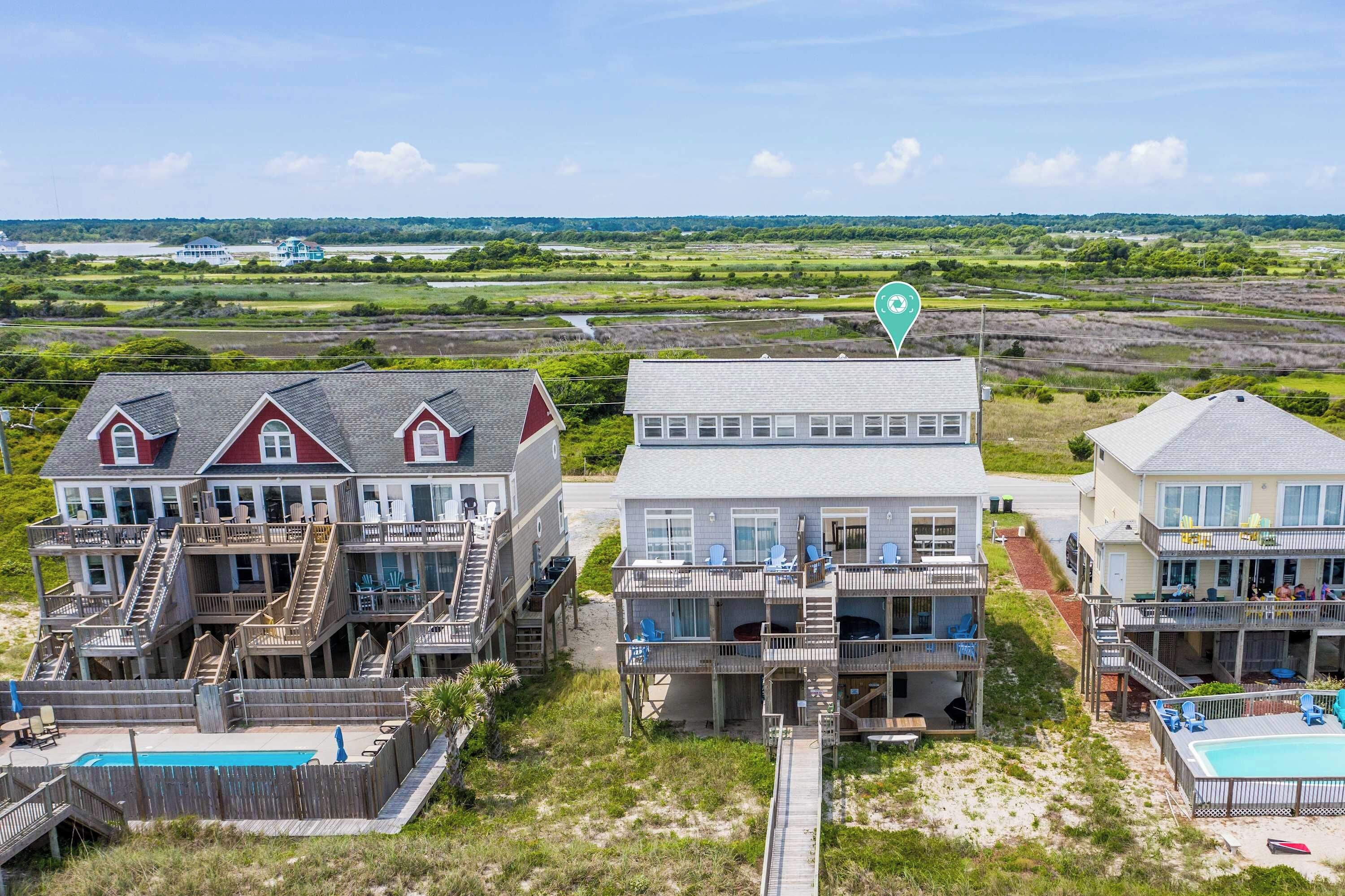 A beachfront property with multiple houses, a swimming pool, and a view of the ocean and distant landscape.