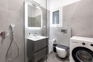 A modern bathroom with a shower, sink, toilet, and washing machine. - Cozyopolis - Timeless 3-BR in Athens  (Athens)
