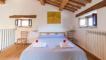 Un dormitorio con una cama grande, cabecera de madera, dos mesitas de noche, una ventana y un radiador.