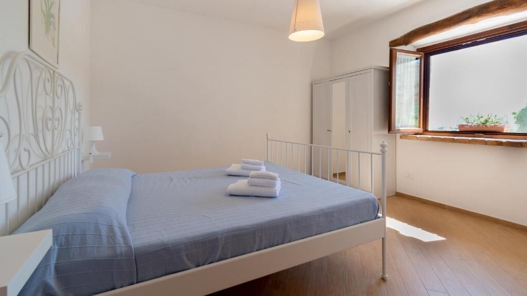 A bedroom with a single bed, a window with a view, and a wardrobe.