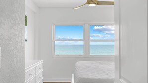 Ein Schlafzimmer mit Meerblick, einem Deckenventilator und einer weißen Kommode.