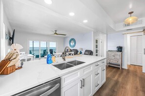 Une cuisine moderne avec des meubles blancs, un grand îlot central doté d’un évier et une vue sur l’extérieur.