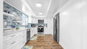 Una cocina moderna con armarios blancos, un refrigerador de acero inoxidable, un microondas y un lavavajillas.