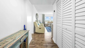 Un pasillo con piso de madera, un sofá color beige, una mesita y vistas al exterior.
