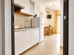 A compact kitchen with a built-in stove, a sink, and a refrigerator. There is a dining area with a table and chairs.