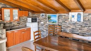 A compact kitchen with wooden cabinets, a stone backsplash, and a dining area with a wooden table and chairs.
