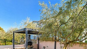 An outdoor patio with a barbecue grill, seating area, and a pergola structure.