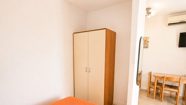 A hotel room with a bed, a wardrobe, a desk, and a chair.