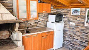 A compact kitchen with a stone backsplash, wooden cabinets, a built-in oven, and a microwave.