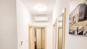 Ein Flur mit hellem Boden, weißen Wänden und einer Decke mit einer eingelassenen Leuchte.