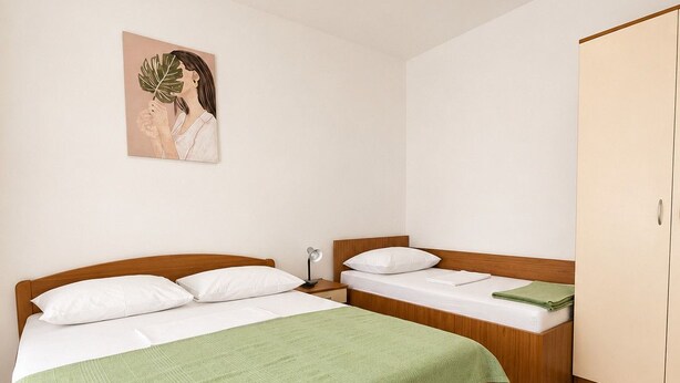 A bedroom with two beds, a green blanket, a bedside lamp, and a wardrobe. - Apartment Olinda (Zaton)