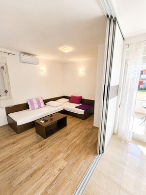A modern living room with a sofa, a coffee table, and a sliding glass door leading to an outdoor area. - Apartment Marcela (Zaton)