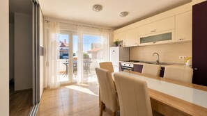 Eine moderne Küche mit Essbereich, einer großen Glasschiebetür, die auf eine Terrasse im Freien führt, und Blick auf die Nachbarschaft.