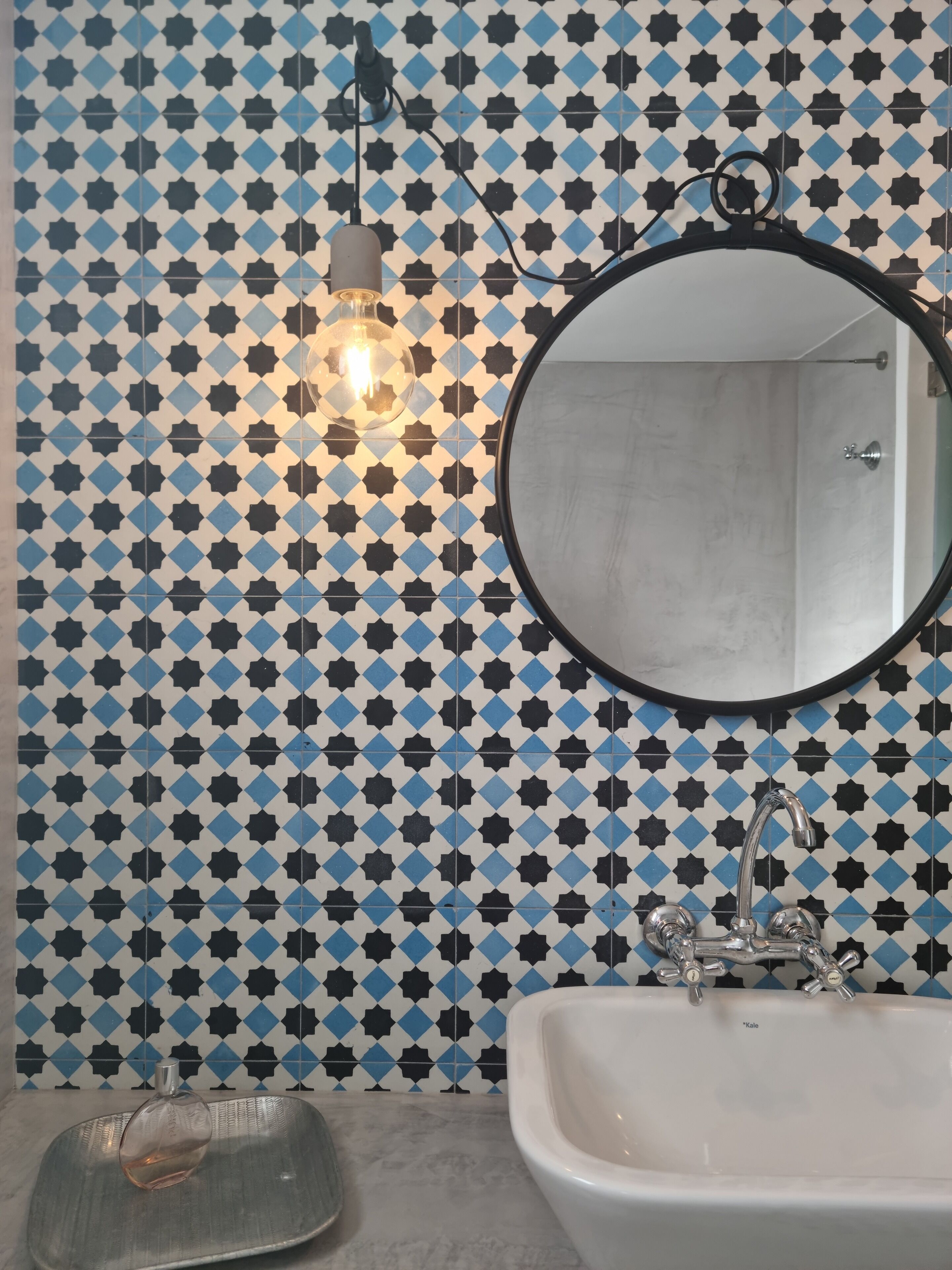 A bathroom with a sink, a mirror, and a light fixture on the wall.