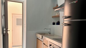 A kitchen with a patterned tile floor, a stainless steel refrigerator, a built-in oven, and a hanging chandelier. - Abella Maison, Kythnos (kythnos)