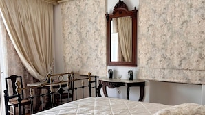 A bedroom with a large bed, a wooden chair, a small table, and a mirror. - Abella Maison, Kythnos (kythnos)