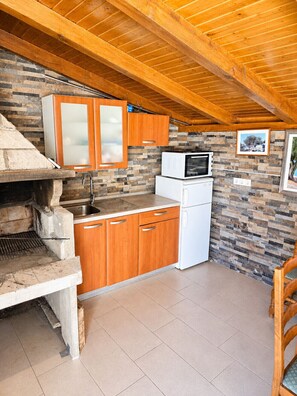 A compact kitchen with a stone backsplash, wooden cabinets, a built-in oven, and a microwave.
