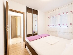 A bedroom with a bed, a wardrobe, and a door leading to another room.