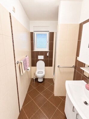 A bathroom with a toilet, a sink, and a window.