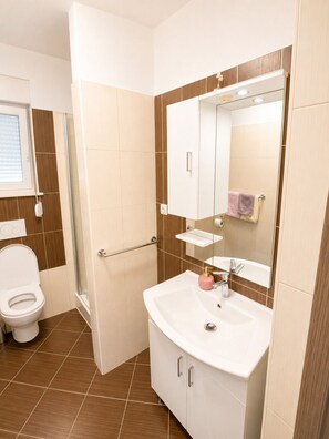 A bathroom with a toilet, shower, sink, and mirror. - Apartment Aora (Zaton)