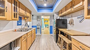 A kitchen with wooden cabinets, a ceiling fan, and a view into the dining area.
