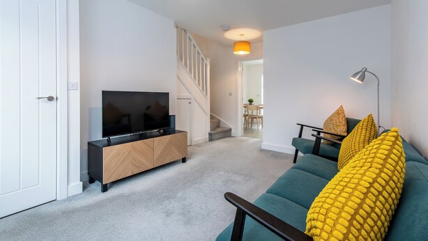 Ein modernes Wohnzimmer mit Fernseher, Sofa und Treppe.
