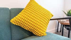 Ein grünes Sofa mit einem gelben Kissen mit Struktur.