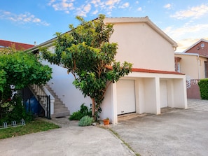 Un immeuble résidentiel avec un garage, un escalier et un arbre dans le jardin avant.