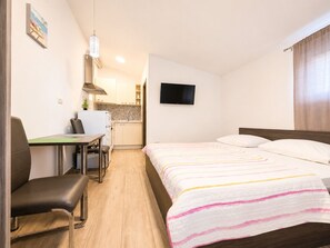 A hotel room with a bed, a desk, a chair, a television, and a kitchenette. - Studio Apartment Nia (Zaton)
