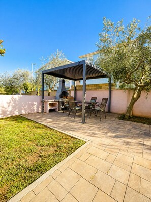 An outdoor patio with a grill, seating area, and a pergola structure. - Studio apartment Vita (Zaton)