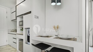 A modern kitchen with white cabinetry, a built-in microwave, and a dining area with a white table and black bar stools. - Bona by Kozystay - Ciumbuleuit (Bandung)