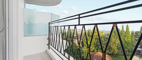 A balcony with a black metal railing, a white wall, and a glass door.