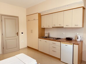 A compact kitchen with a sink, stove, and a small refrigerator.