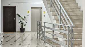 A hallway with a tiled floor, a potted plant, a door marked '32', and a staircase with a metal railing. - Thoma's K Studios - Double Studio (Vlorë)