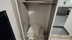 A compact room with a bed, a television, and a small shelf.