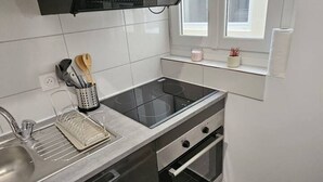 A modern kitchen with a stainless steel countertop, a built-in oven, and a black induction cooktop.