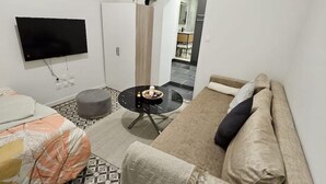 A modern living room with a sofa, a coffee table, and a TV mounted on the wall.